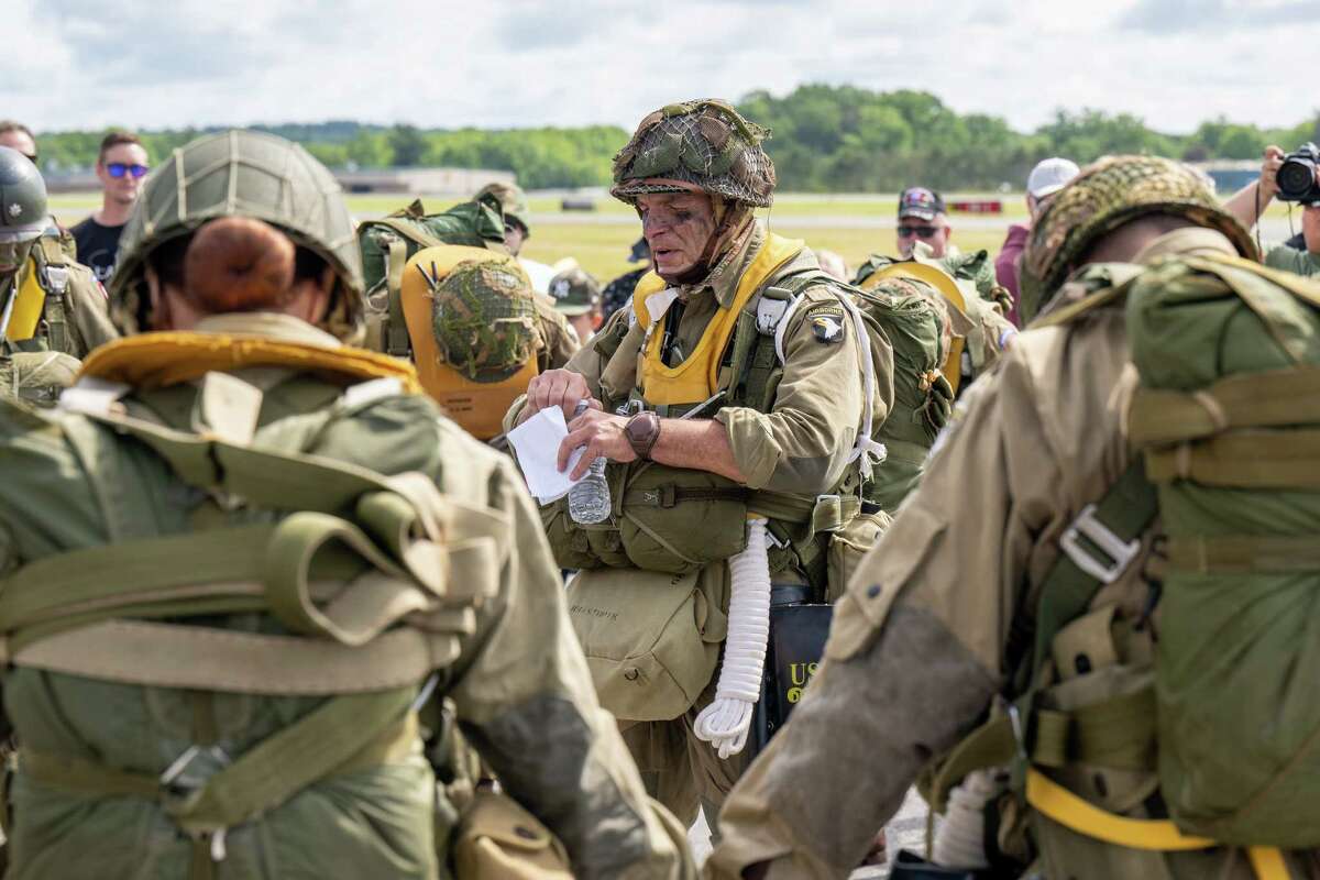 Members of the Airborne Demonstration Team, wearing authentic gear identical to paratroopers on D-Day in 1944, say a prayer before jumping out of a C-47 that flew on D-Day during an exhibition at the third annual Wings & Wheels showcase to benefit the Prescott Foundation, which restores and maintains WWII aircraft and vehicles, at the Hangar at 743, on Saturday in Colonie.