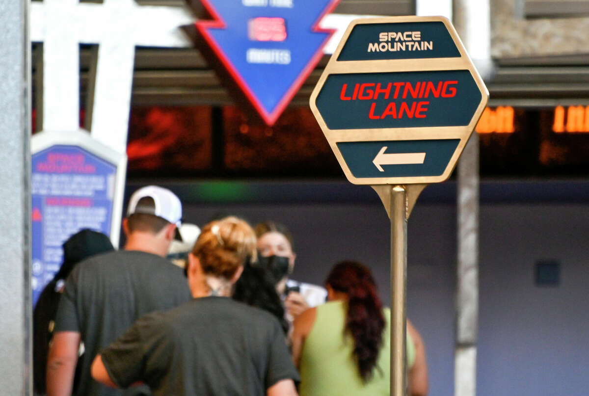 Guests wait near the Lightning Lane sign at Space Mountain in Tomorrowland at Disneyland Park in Anaheim, Calif.