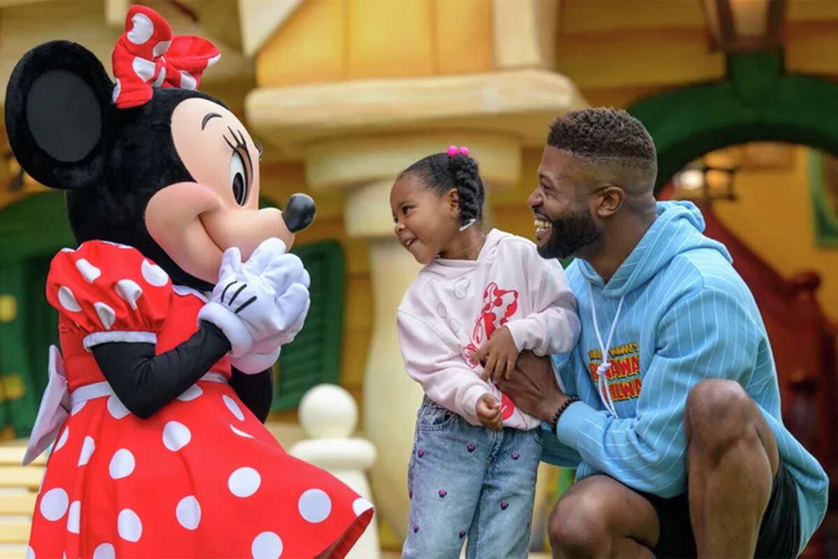 Minnie greets a little girl and her dad at Disneyland Resort in Anaheim, Calif.