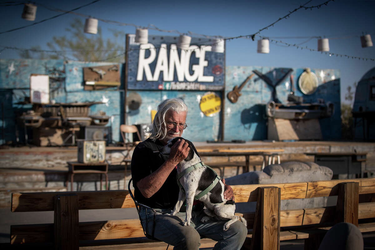 Bill Builder Bill Ammon, 72, a Slab City resident for 22 years, sits with his dog Sparky in his empty live music venue, The Range, due to the pandemic restrictions, at Slab City. April 21, 2021