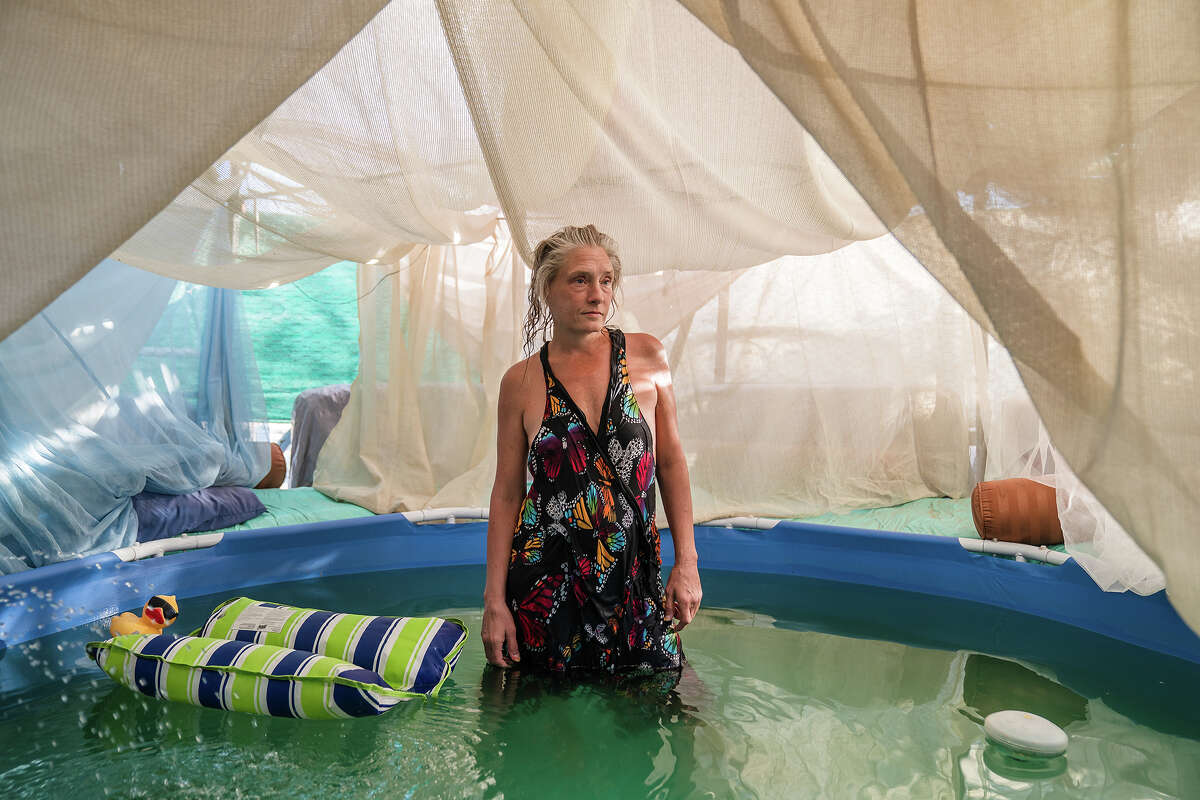 Dot of House of Dots art gallery stands in her pool to cool off amid a heatwave on August 31, 2022 in Slab City near Niland, California.