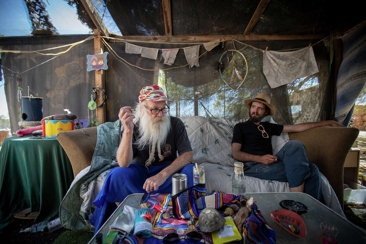 FILE - Bob Johnson, 68, left, and Matt Crow, 31, relax at Johnsons Slab City Hostel April 21, 2021 in Slab City, Calif.