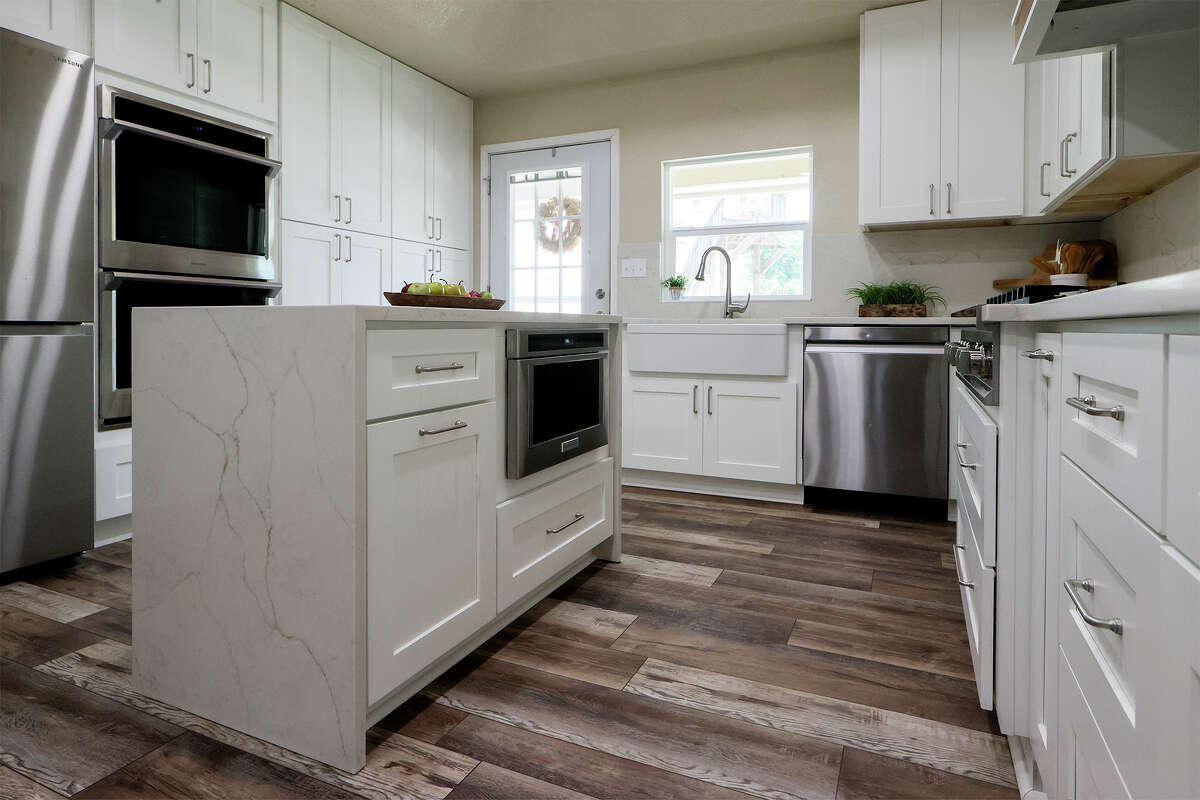 Both kitchen islands are topped with a warm white quartz shot through with thin veins of bronze and gray and that waterfalls down the shorter sides