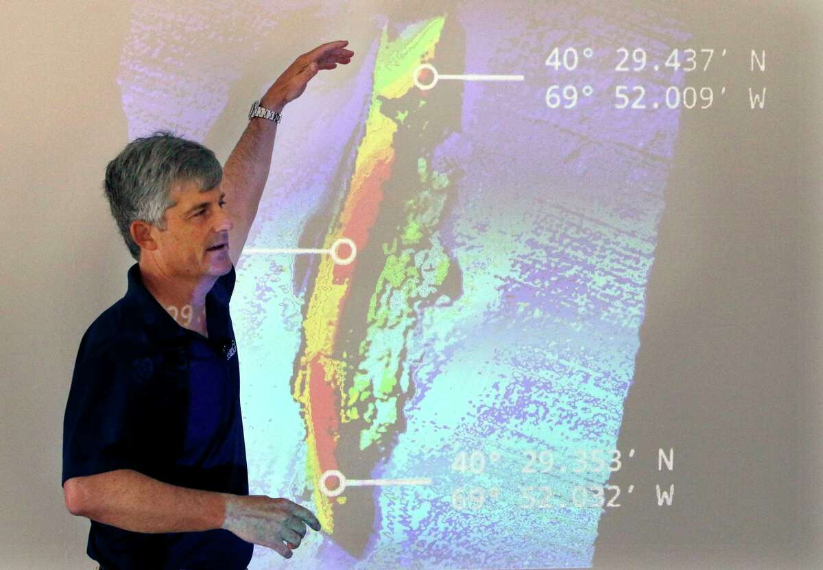 OceanGate CEO and co-founder Stockton Rush speaks in front of a projected image of the wreckage of the ocean liner Andrea Doria. Rescuers in a remote area of the Atlantic Ocean are racing against time to find a missing submersible before the oxygen supply runs out for five people, including Rush. 