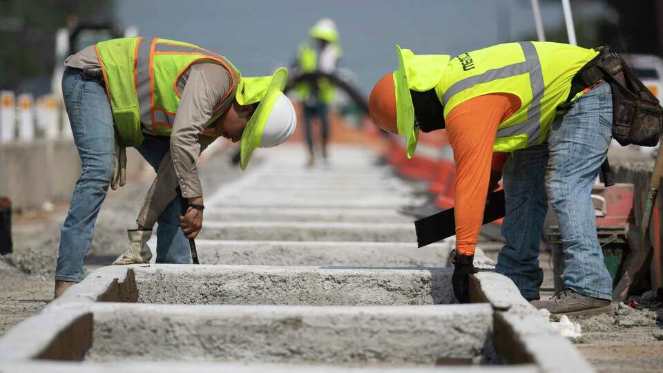 Construction workers continue progress on additional lanes along Texas 105, taking water and rest breaks under a large, blue tent on Wednesday, June 21, 2023 in Conroe.