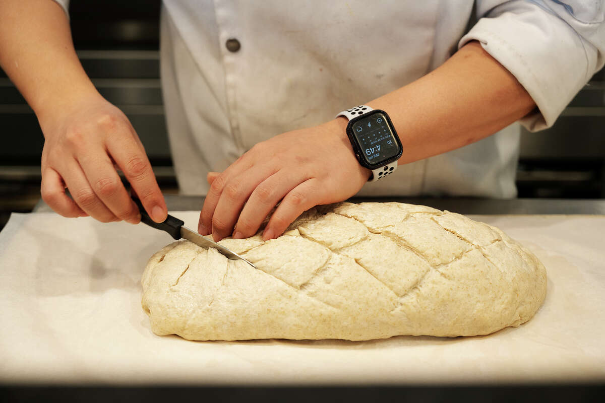 Chef cuts into bread dough at Croissante in Santa Clara Calif., June 20, 2023