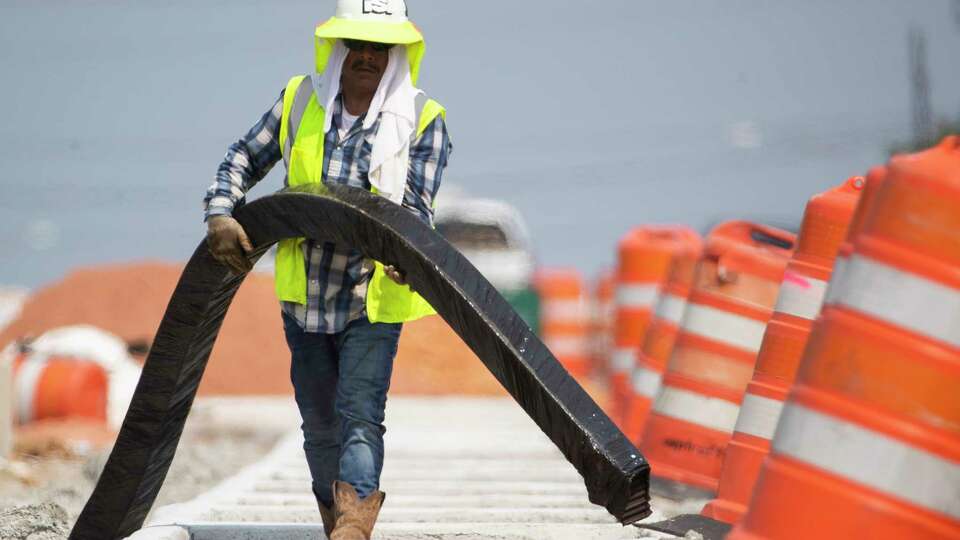 Construction workers continue progress on additional lanes along Texas 105, taking water and rest breaks under a large, blue tent on Wednesday, June 21, 2023 in Conroe.