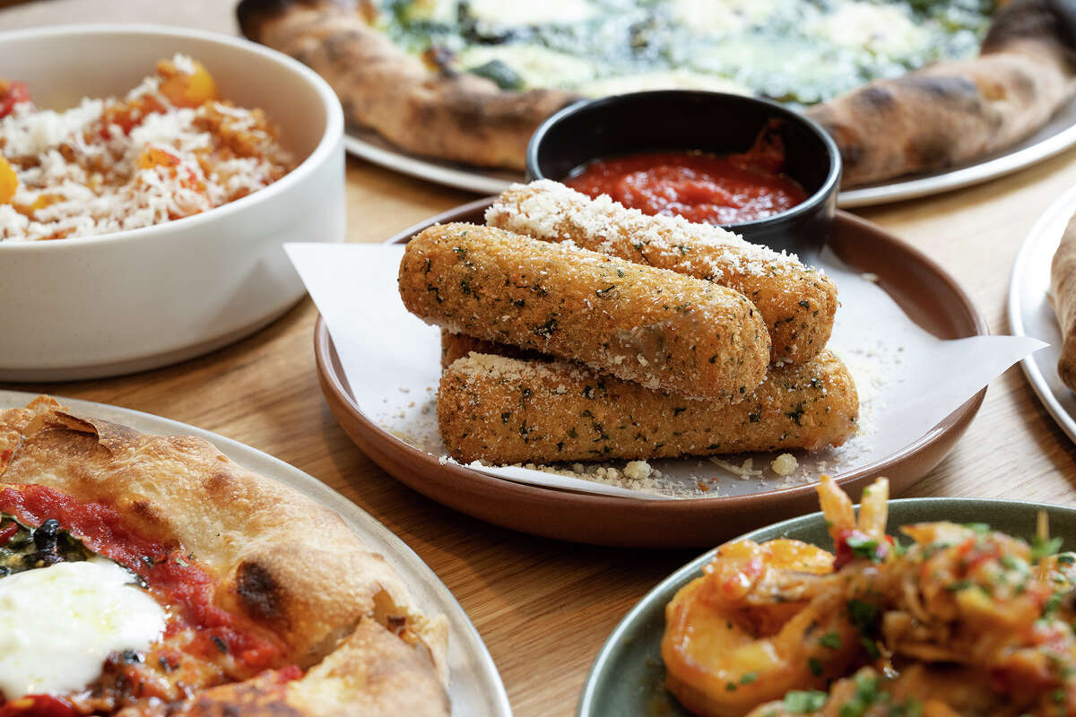 Clockwise from left, the heirloom tomatoes starter, pesto pizza, mozzarella sticks, shrimp scampi and burrata pizza at Flour + Water Pizzeria in San Francisco on June 22, 2023.