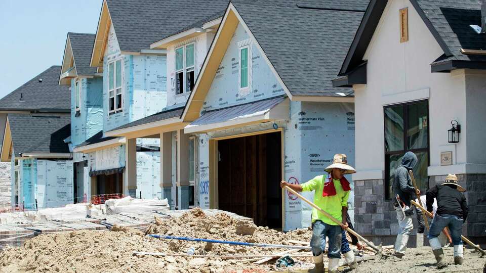 Workers pour concrete for a driveway as home construction continues near Conroe ISD's Christopher J. Hines Elementary, Wednesday, June 28, 2023, in Spring.