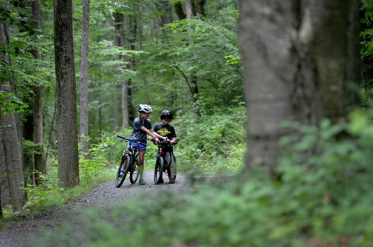 11yr old Ava Malagisi from Ridgefield helps her younger brother Max get the bell on his bicycle to ring while riding as their mothers walk on the Norwalk River Valley Trail along the Wilton Loop portion on Tuesday July 25, 2017 in Wilton Conn.