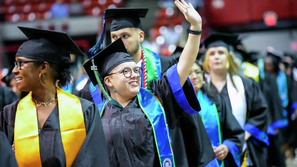 A graduate waves to her friends and family during the procession for UH Clear Lake's College of Human Sciences and Humanities and College of Science and Engineering graduation ceremony at NRG Arena on Saturday, May 13, 2023 in Houston.