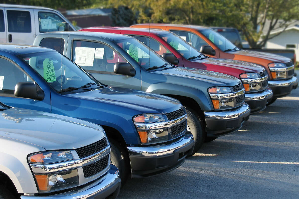 A row of new trucks lined up on a dealer's lot. 