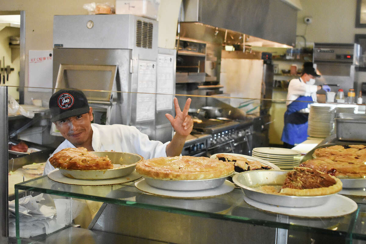 A member of the kitchen crew waves at Joe’s Cafe in Santa Barbara, Calif., on May 31, 2023. 