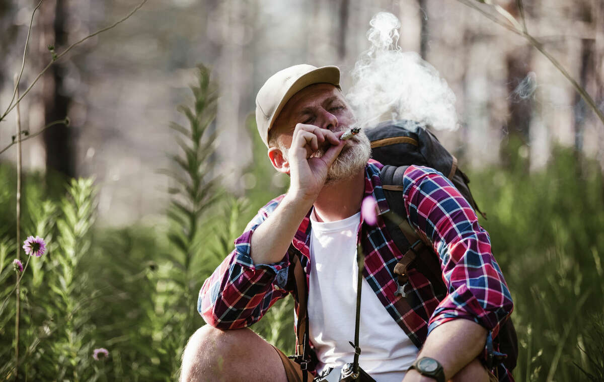 A man smokes a joint while camping in the woods.