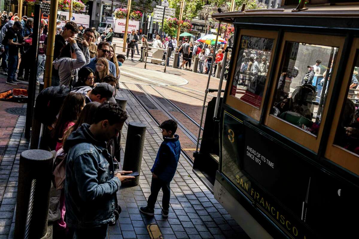 Visitors wait to ride the historic cable car at the turntable on Powell and Market streets in San Francisco.