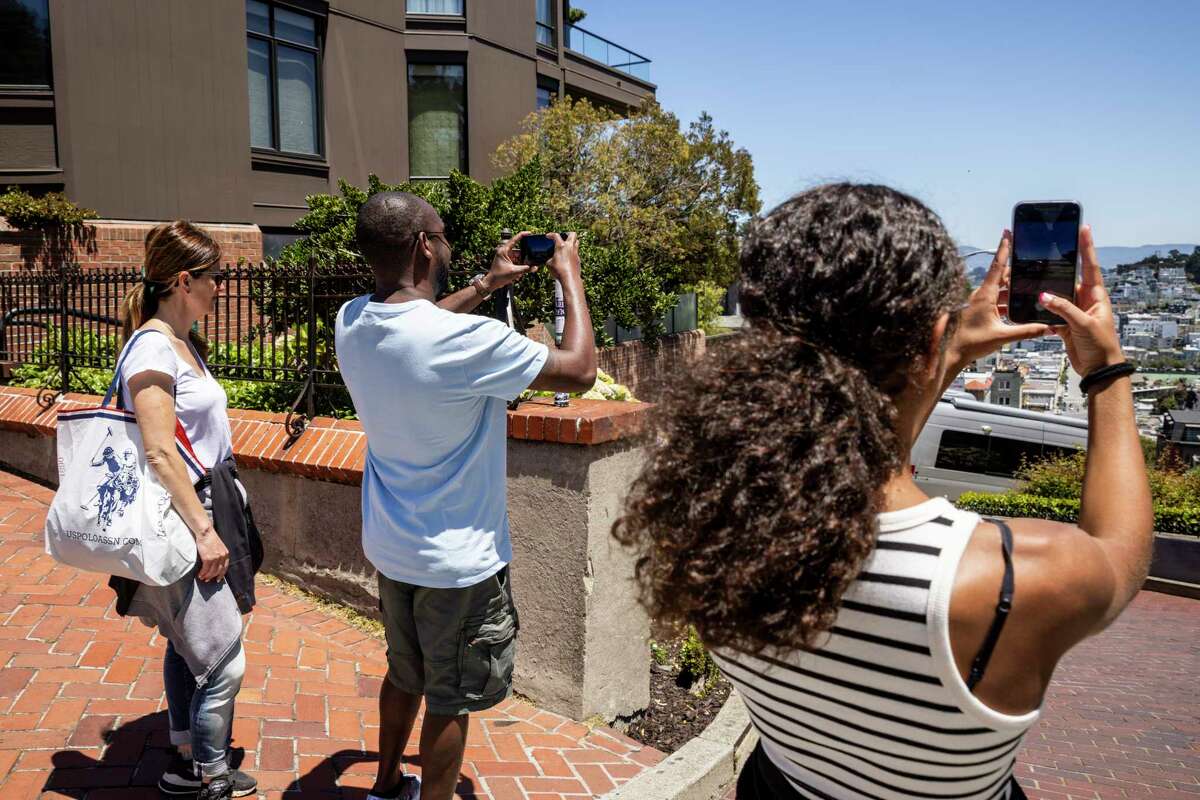 Christine Chirao (left) watches as husband Jeff and daughter Fiona take photos on Lombard Street during their visit from France.
