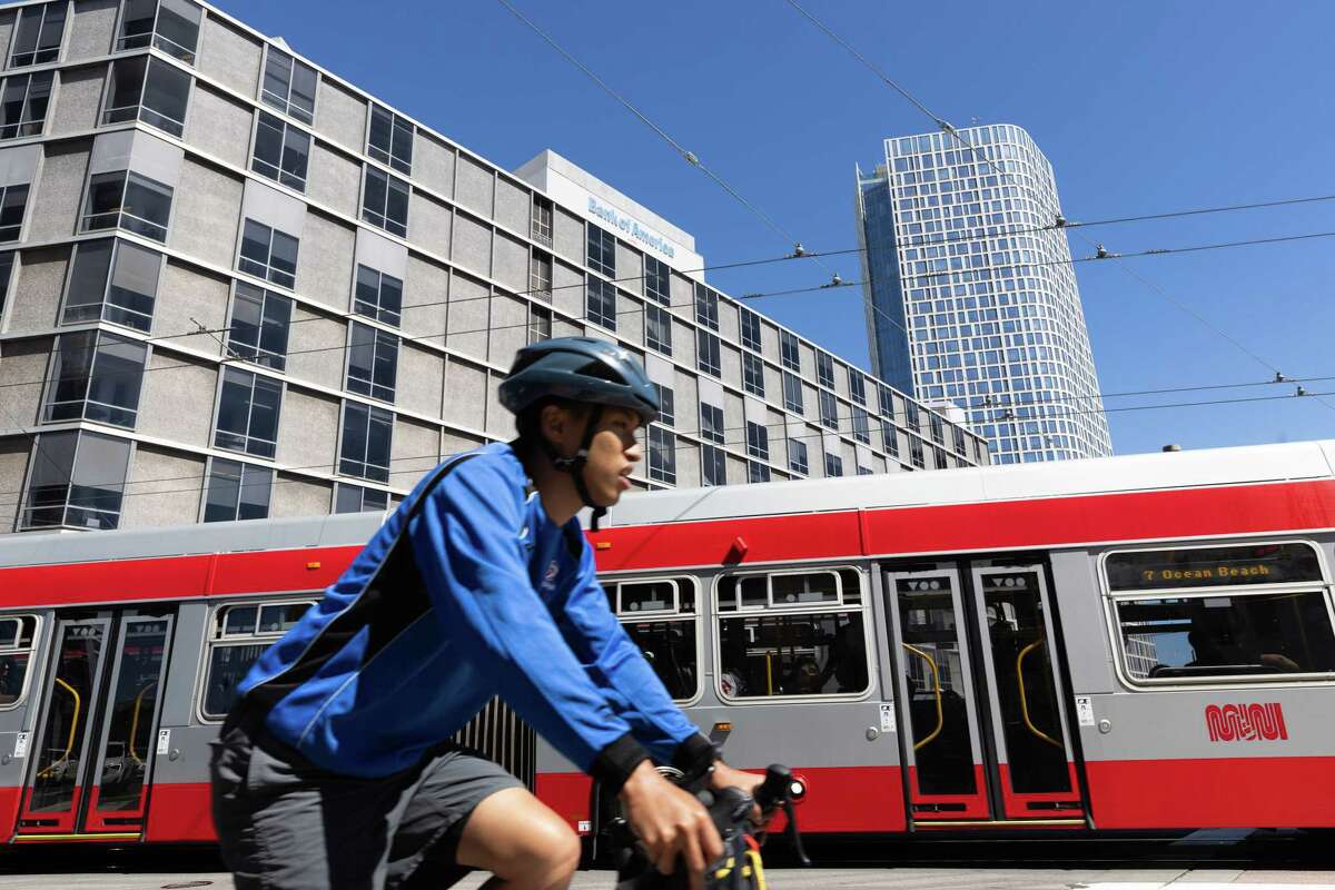 A bicyclist rides along Market Street past the building where the SFMTA headquarters is located on Van Ness Avenue in San Francisco. The transit agency says it is looking into using artificial intelligence in some capacities.