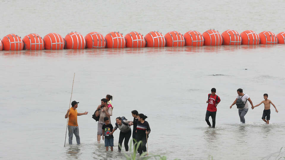 Migrants walk on the U.S. side of a buoys system on the Rio Grande south of Eagle Pass, Texas, Wednesday, July 12, 2023.