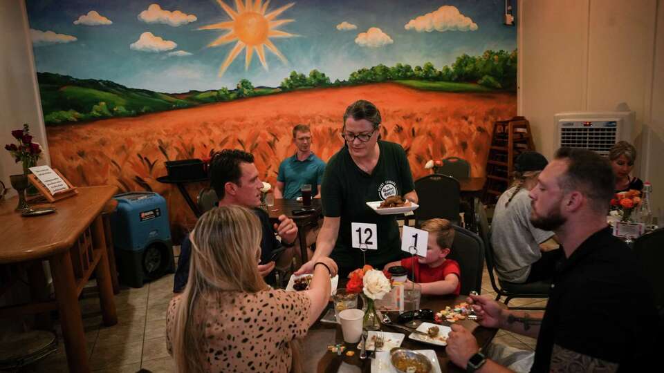 A woman serves food to Stevie Minner, front left, her husband Ryan to her left, their son Justice, 4, and James Greene, a family friend at front right, as they dine Tuesday, July 18, 2023, at the Abundant Harvest Kitchen and Bistro in Spring. The three adults eating are all veterans, and they said they try to support the mission of the bistro by dining there as often as possible.