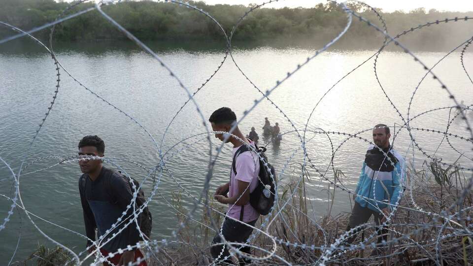 Migrants walk the banks and wade the waters of the Rio Grande in an attempt to reach an entry point several miles south of Eagle Pass, Texas, Thursday, July 20, 2023. The entry, set up as part of Operation Lone Star, is on land whose owner has agreed to press trespassing charges. Texas will arrest single men and women. Families are released into U.S. Border Patrol custody.