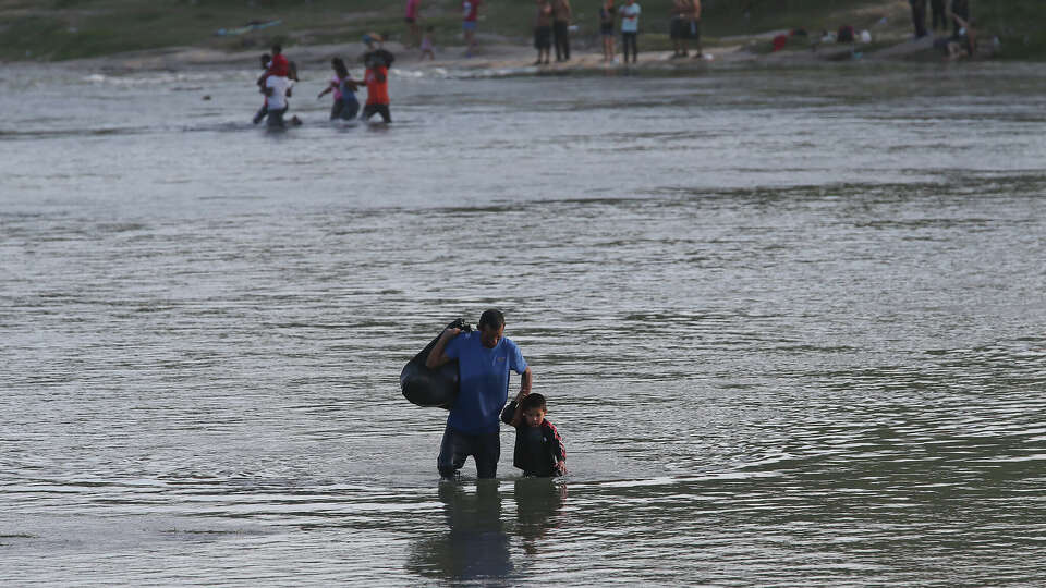 Migrants cross the Rio Grande from Piedras Negras, Mexico into Eagle Pass, Texas, Thursday, July 20, 2023. With Operation Lone Star, Texas has set up a barrier of box cars and concertina wire to deter migrants from entering the U.S. through the state. They are forced to wade the water or walk the banks to an entry point several miles south of Eagle Pass.