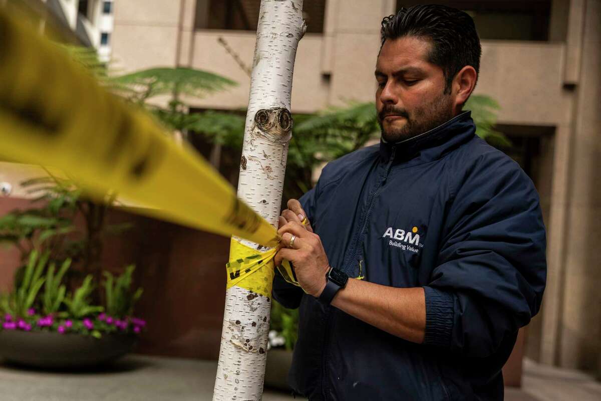 Jose Castillo, a foreman in charge of janitorial services at a downtown office building, cordons a courtyard with tape during cleaning in San Francisco. 