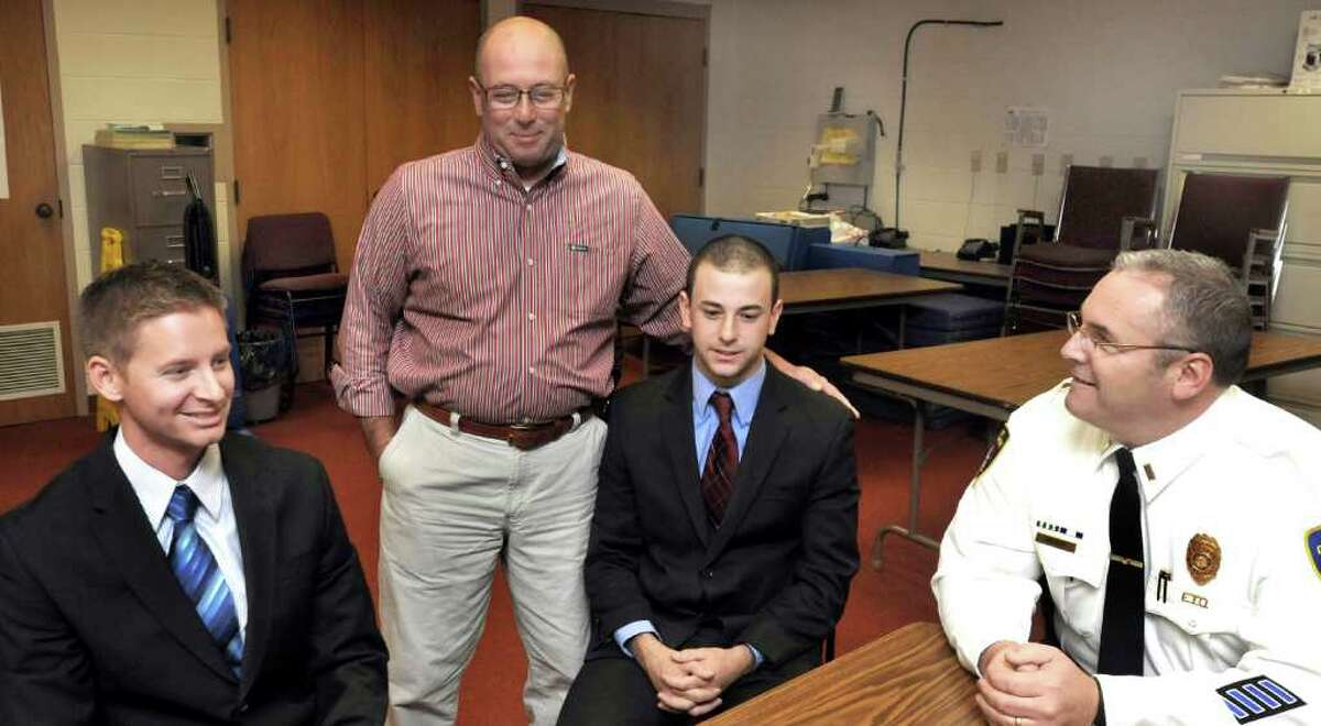 State Police Academy recruits Rayden Arnold, left, and Collin Marino, seated center, both 25, talk with New Milford police officers Henry Marino, center, and Mark Buckley, right, at New Milford police headquarters , Thursday, Oct. 21, 2010. Collin is Henry's son.