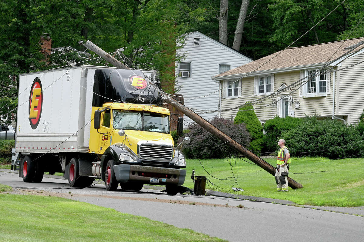 Town of Vernon Assistant Fire Chief Rob Babcock talks to the driver of the tractor trailer after taking down two poles on Monday, July 24, 2023, in Vernon. The driver was uninjured but couldn't leave the cab until the power was cut. The accident happened on Valerie Drive in a quiet residential neighborhood around 12:30 p.m. The truck became tangled in low-hanging power lines that wrapped around the top of the trailer. The truck took out two utility poles before coming to a stop. Fire officials asked the power company to shut down the power in the area so the driver could get out safely.