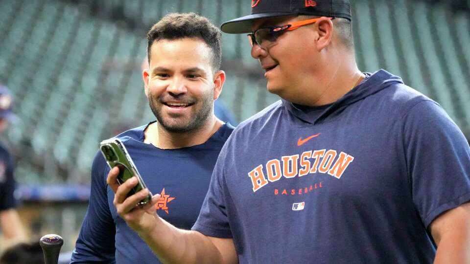 Jose Altuve looks at Omar Lopez's phone during batting practice before the start of an MLB baseball game at Minute Maid Park on Monday, July 24, 2023 in Houston.