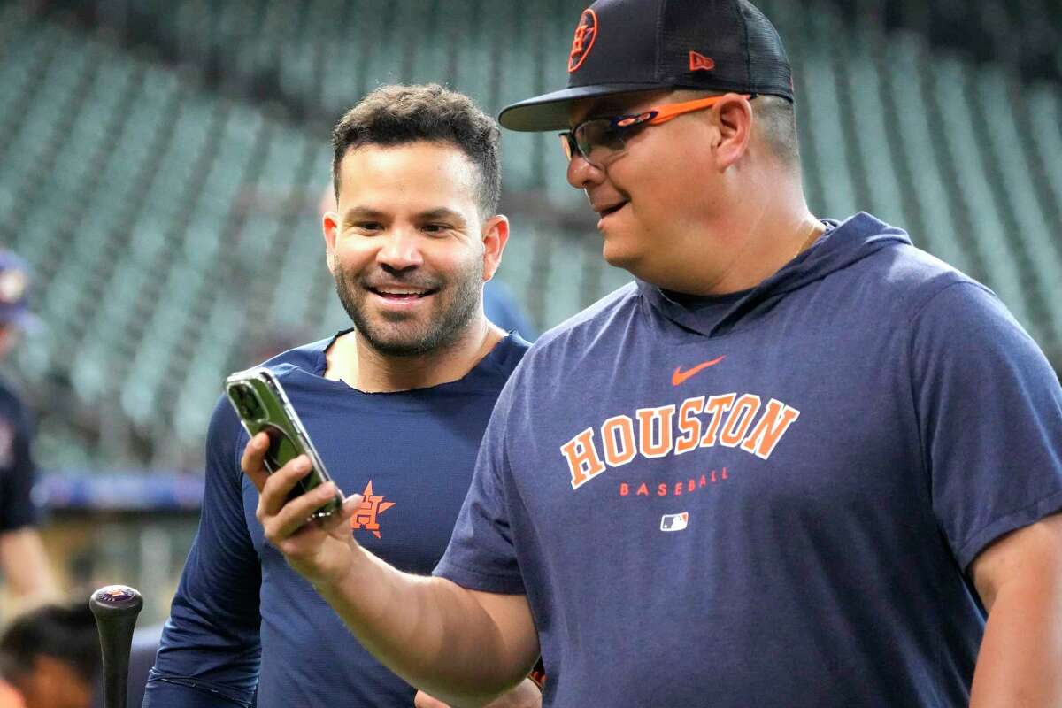 Jose Altuve looks at Omar Lopez's phone during batting practice before the start of an MLB baseball game at Minute Maid Park on Monday, July 24, 2023 in Houston.