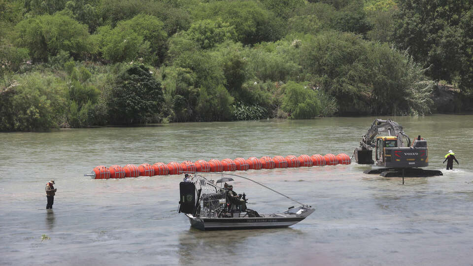 Workers float a series of connected buoys on the Rio Grande south of Eagle Pass, Texas, Tuesday, July 11, 2023.