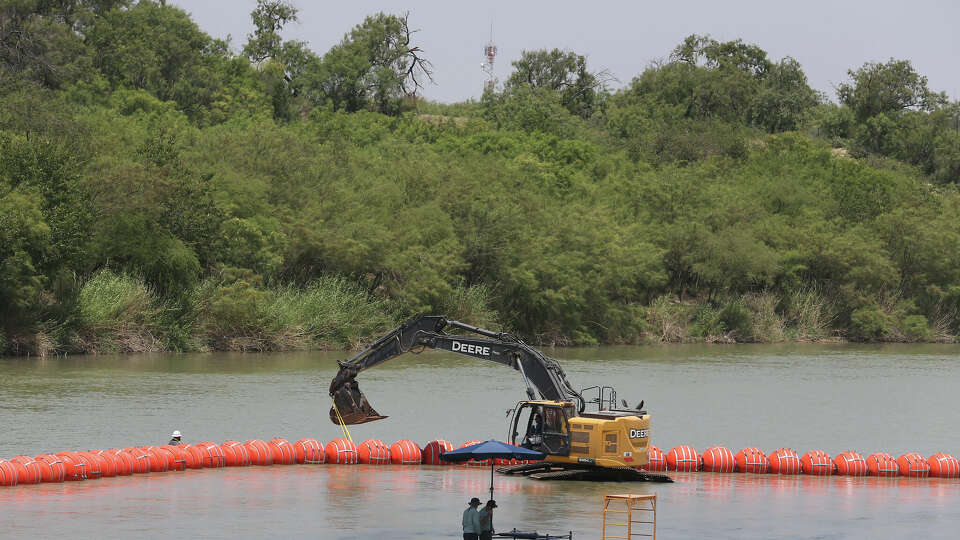 Workers place scaffolding by buoys on the Rio Grande south of Eagle Pass, Texas, Wednesday, July 12, 2023.