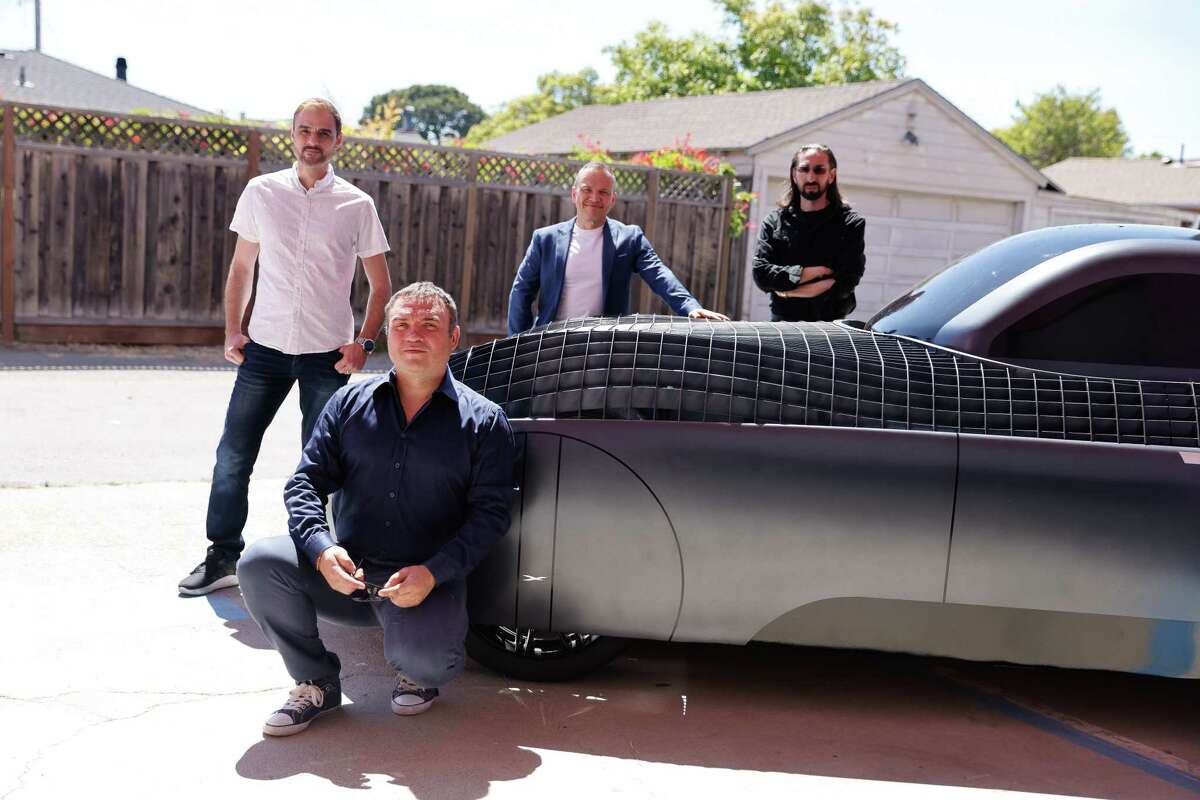 Constantine Kisly, kneeling, VP of Engineering; Pavel Markin, standing left to right, VP of Electronics; Oleg Petrov, VP of R&D and Jim Dukhovny, CEO; stand for a portrait with the display model of their Alef flying car.