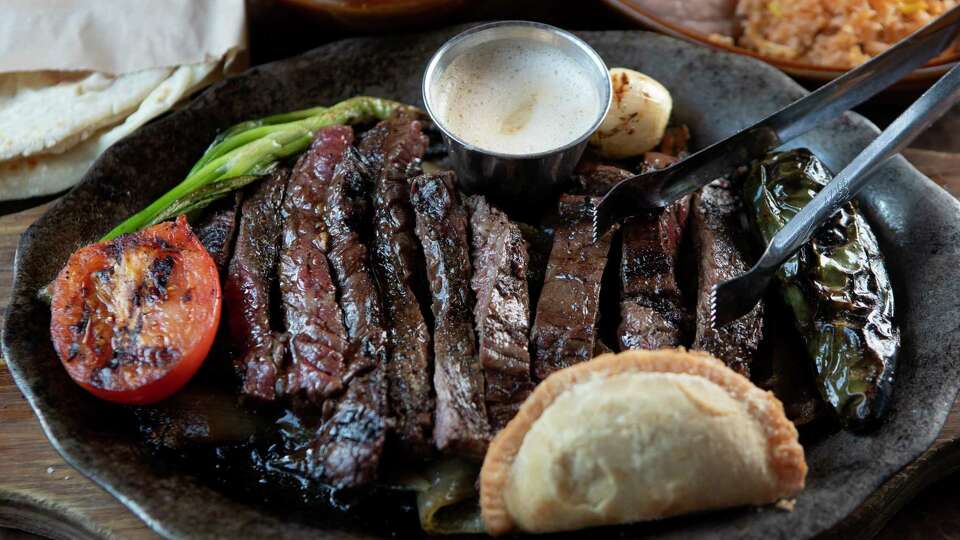 The beef fajita platter is seen at Goode Co. Kitchen & Cantina, Thursday, Aug. 3, 2023, in Houston. The dish is served alongside a pork green chili stew empanada and chili lime butter.