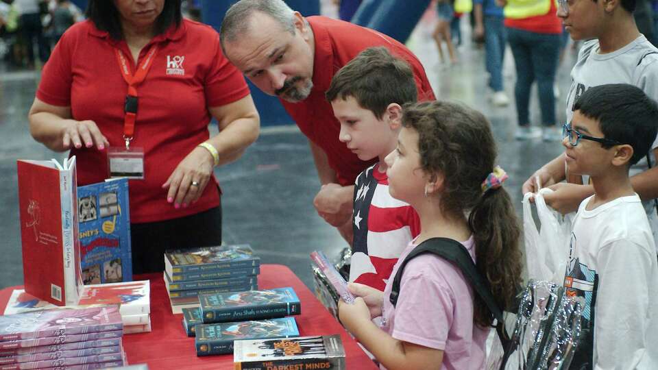 Dad, Farid Garda, helps Malik and Emily pick out books at the Houston Public Library Mobile Express booth during the annual mayor’s Back to School Fest Saturday, Aug. 5 at George R. Brown Convention Center.