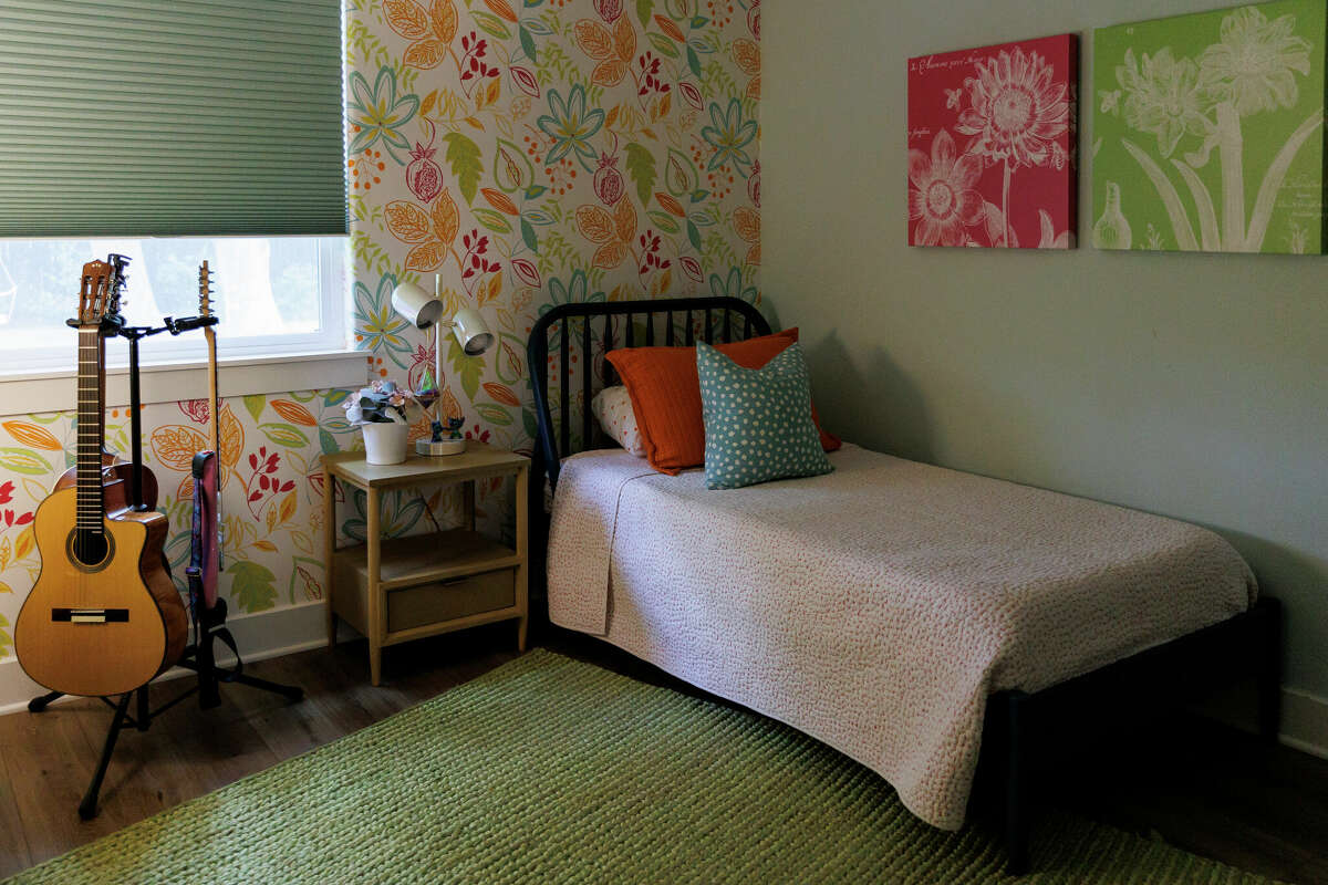 Both the girls' bedrooms have one wall covered in beautifully designed, floral-patterned wallpaper. 