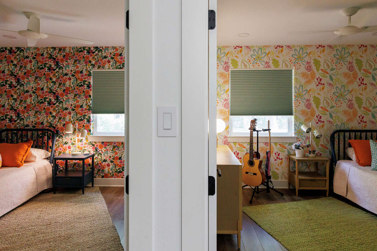 The girls' bedrooms, located side by side, each have a wall covered in beautifully designed, floral-patterned wallpaper.
