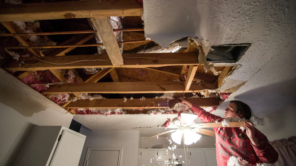 Hannah Siqueiros, clears insulation from a damaged ceiling after a broken pipe was repaired pipe above the kitchen in Michelle Toy's home Wednesday, Feb. 17, 2021 in Spring. Water from a damaged pipe above the kitchen caused the ceiling to collapse.