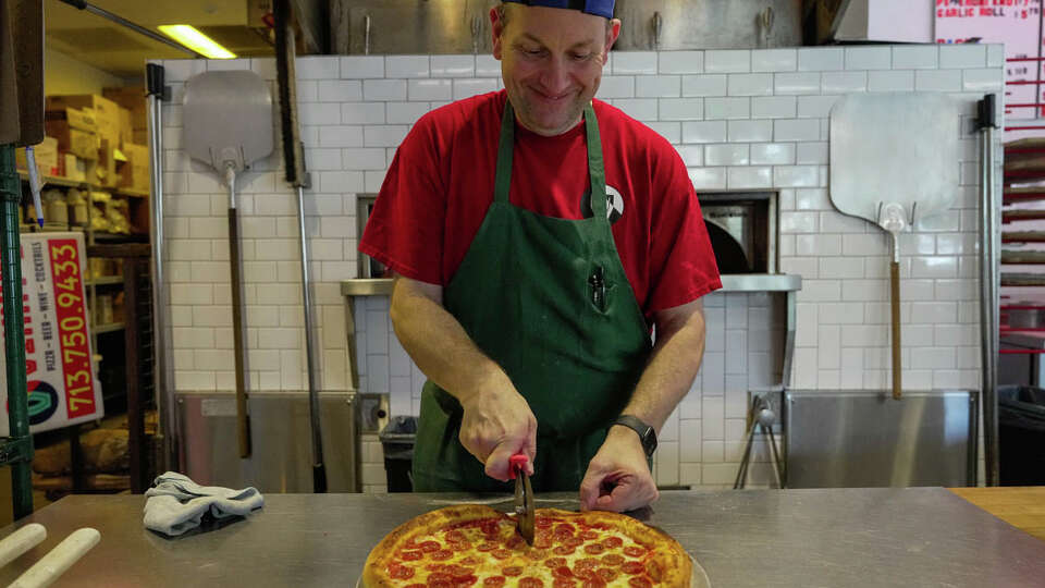 Paul Lewis, executive chef of Vinny's Pizza cuts a pizza into slices on Tuesday, Aug. 8, 2023, in Houston.