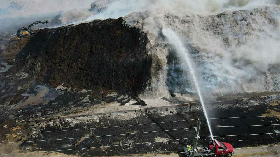 Contractors and crews work on containing a mulch fire at Living Earth on Crawford Street on Monday, Aug. 14, 2023 in Houston. The fire started Sunday evening.
