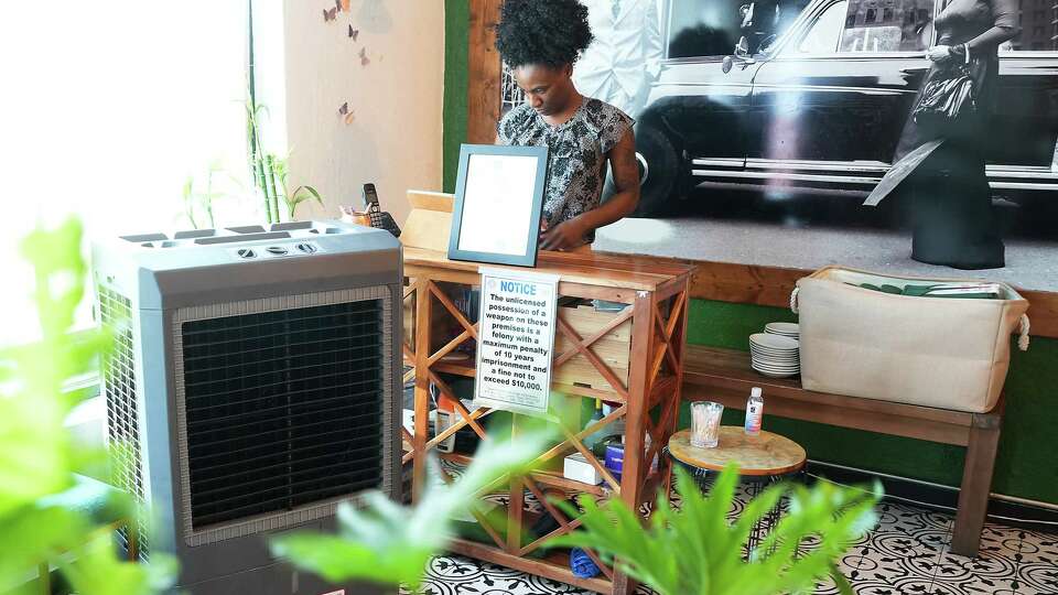 Kau Ba hostess Kia Hinnant waits at the hostess stand near a large cooling unit on Tuesday, Aug. 15, 2023 in Houston. Like other restaurants, Kau Ba has taken extra measures to keep it's restaurant cool during this record-breaking heatwave.