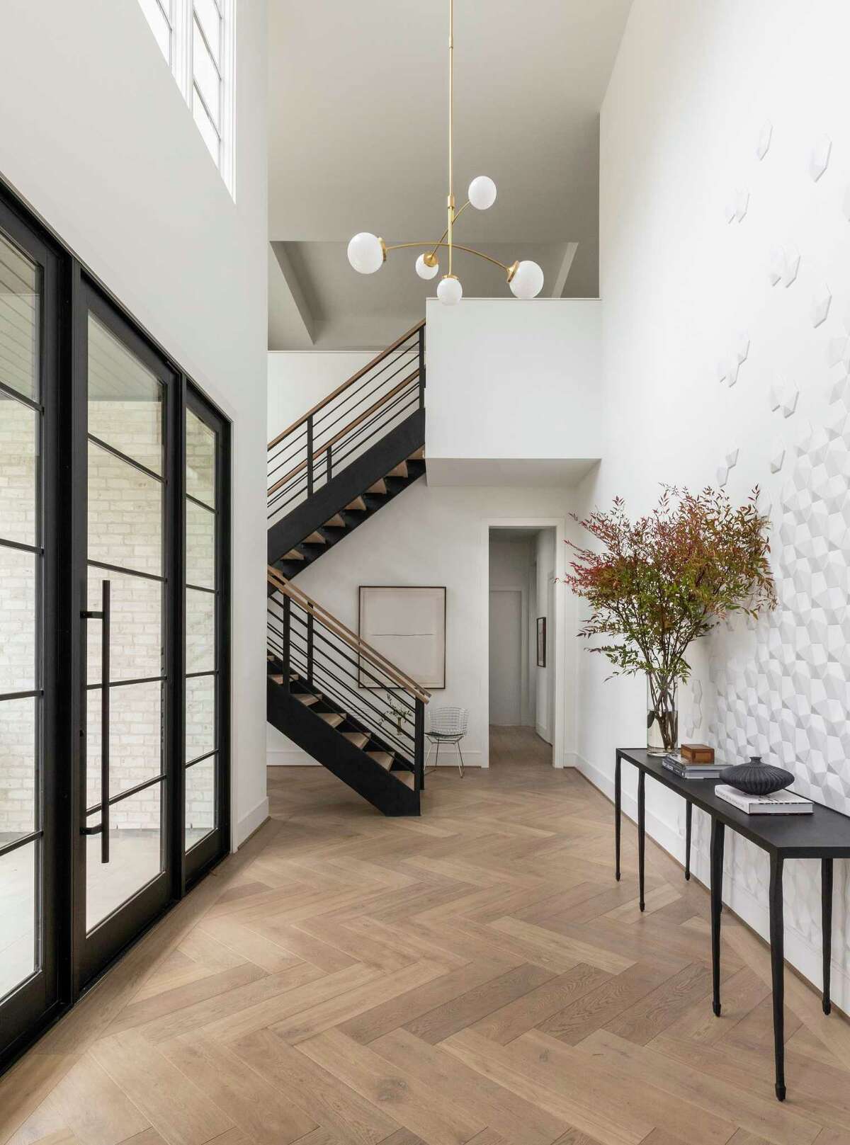 Big door panels, wood flooring laid herringbone style and a pretty console decorate the wide foyer.