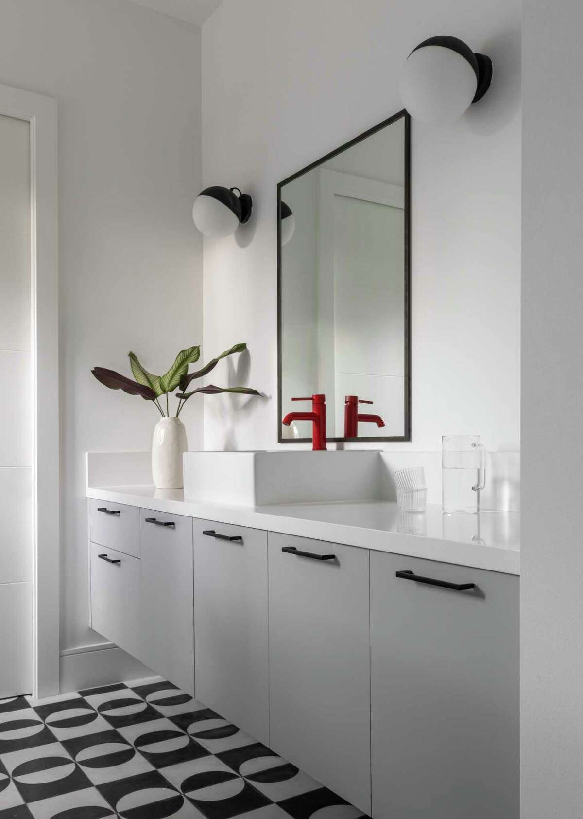 Their other son's bathroom has black and white floor tile with a pop of red in the faucet.