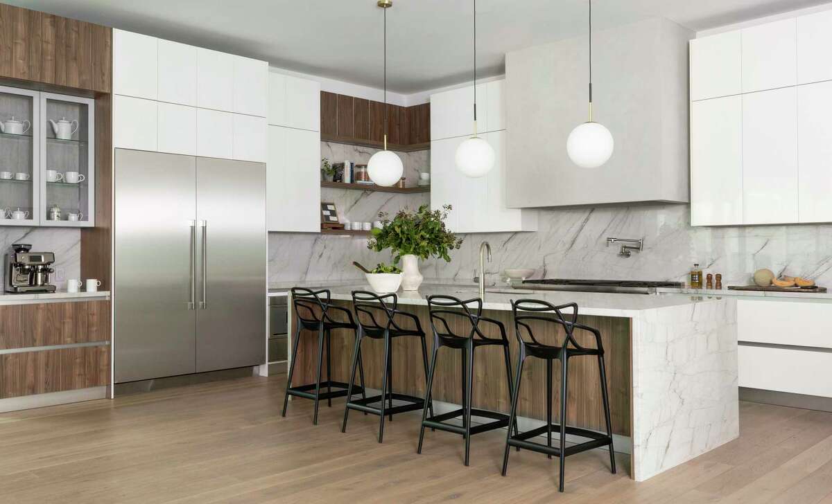 Cabinets and the island are a combination of white finish and wood panels, including a coffee bar with glass-front cabinets.