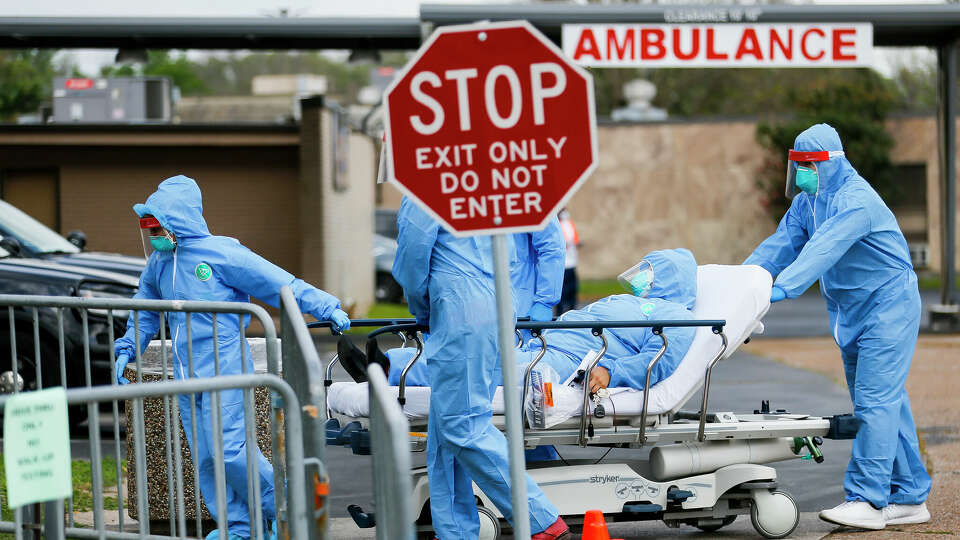 Medical personnel transport a patient from their car to an isolation area after the person displayed severe symptoms when they drove up in their car to be tested at the drive-thru testing center that opening, Thursday morning, March 19, 2020, at the United Memorial Medical Center in Houston.