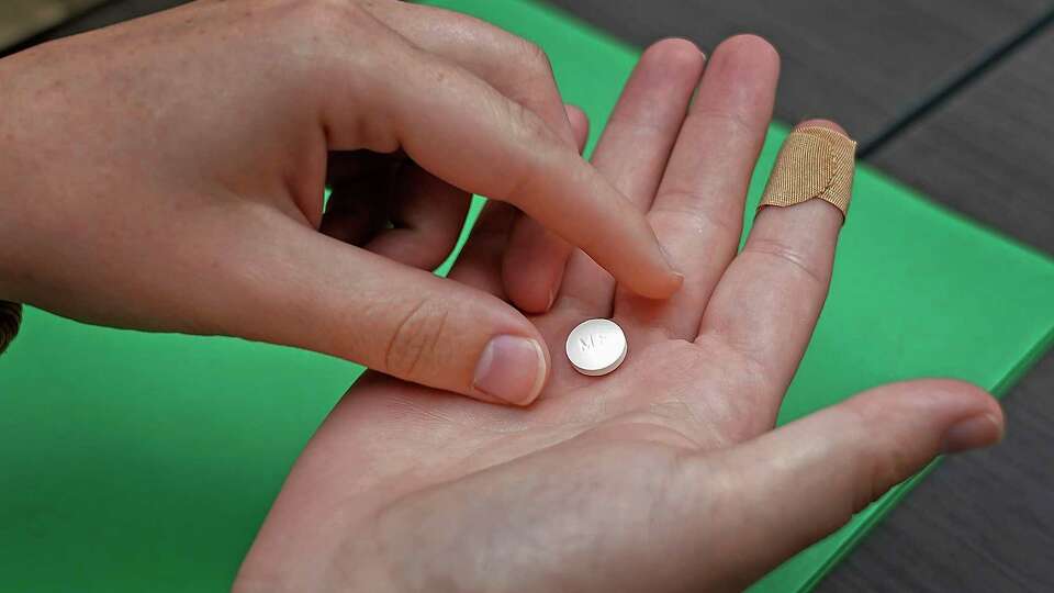 FILE - A patient prepares to take the first of two combination pills, mifepristone, for a medication abortion during a visit to a clinic in Kansas City, Kan., on, Oct. 12, 2022. New restrictions on access to the drug used in the most common form of abortion would be imposed under a federal appeals court ruling issued Wednesday, Aug. 16, 2023, but the Supreme Court will have the final say.