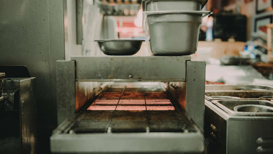 A dirty conveyer oven in a restaurant kitchen