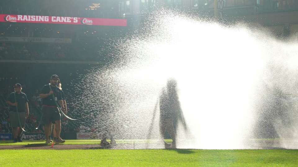 Houston Astros grounds crew spraying water at the infield before the MLB game against the Seattle Mariners on Friday, Aug. 18, 2023 at Minute Maid Park in Houston.