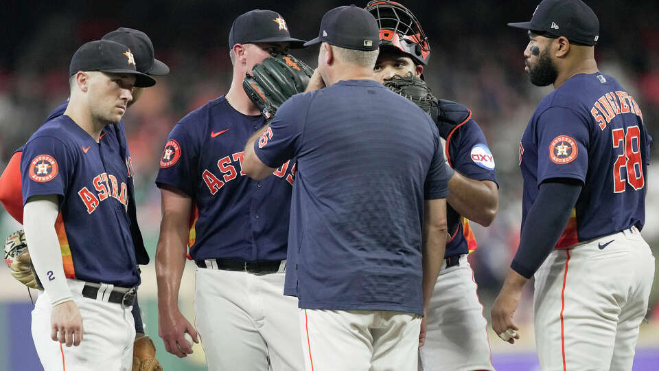 Houston Astros starting pitcher Hunter Brown, center left, talks to pitching coach Josh Miller during the first inning of a Major League Baseball game on Sunday, Aug. 20, 2023, in Houston.