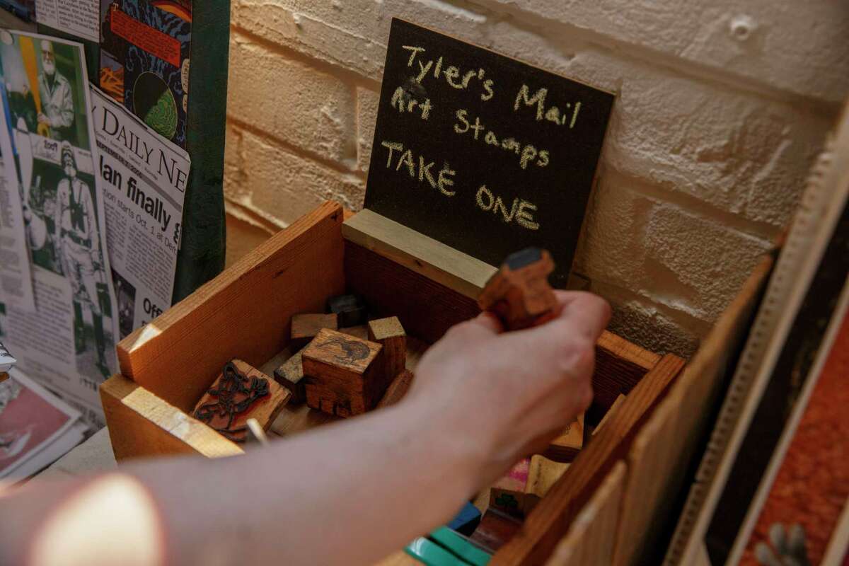 Attendees look through Tyler James Hoare’s mail stamps during the memorial service at Compound Gallery in Emeryville.